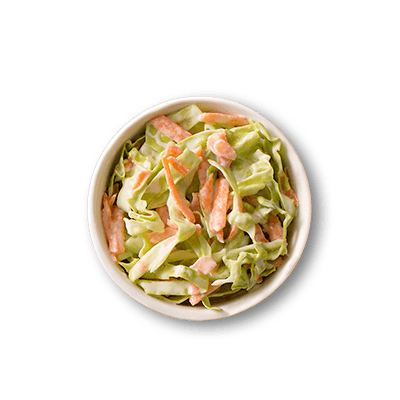 Fresh coleslaw in a white bowl, with shredded green cabbage, orange carrots, and creamy dressing.