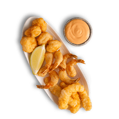 Crispy battered fried calamari and hake nuggets served on an oval white platter with a lemon wedge and dipping sauce.