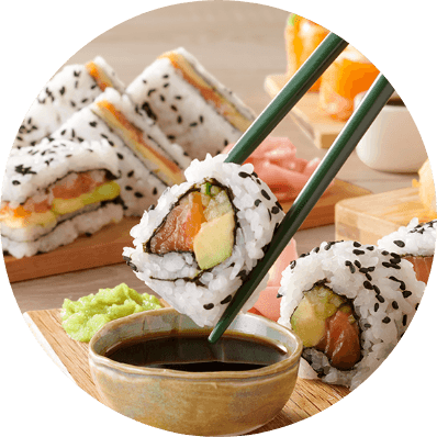 Salmon and avocado sushi roll held with chopsticks above soy sauce