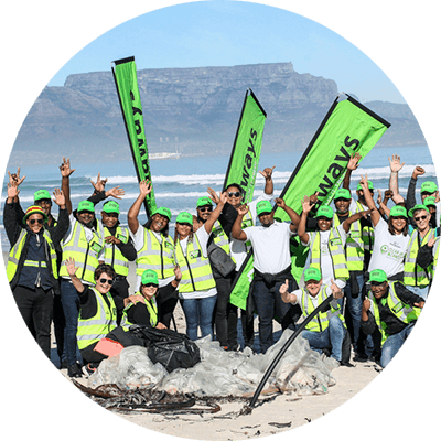 Beach clean-up volunteers posing together with Table Mountain behind them
