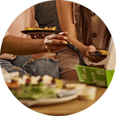 Two friends serving and sharing food together at a table
