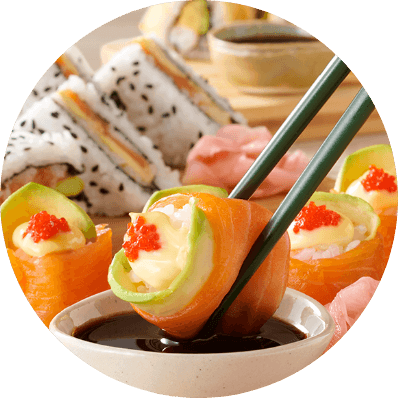 Salmon avocado sushi rolls being dipped in soy sauce with chopsticks