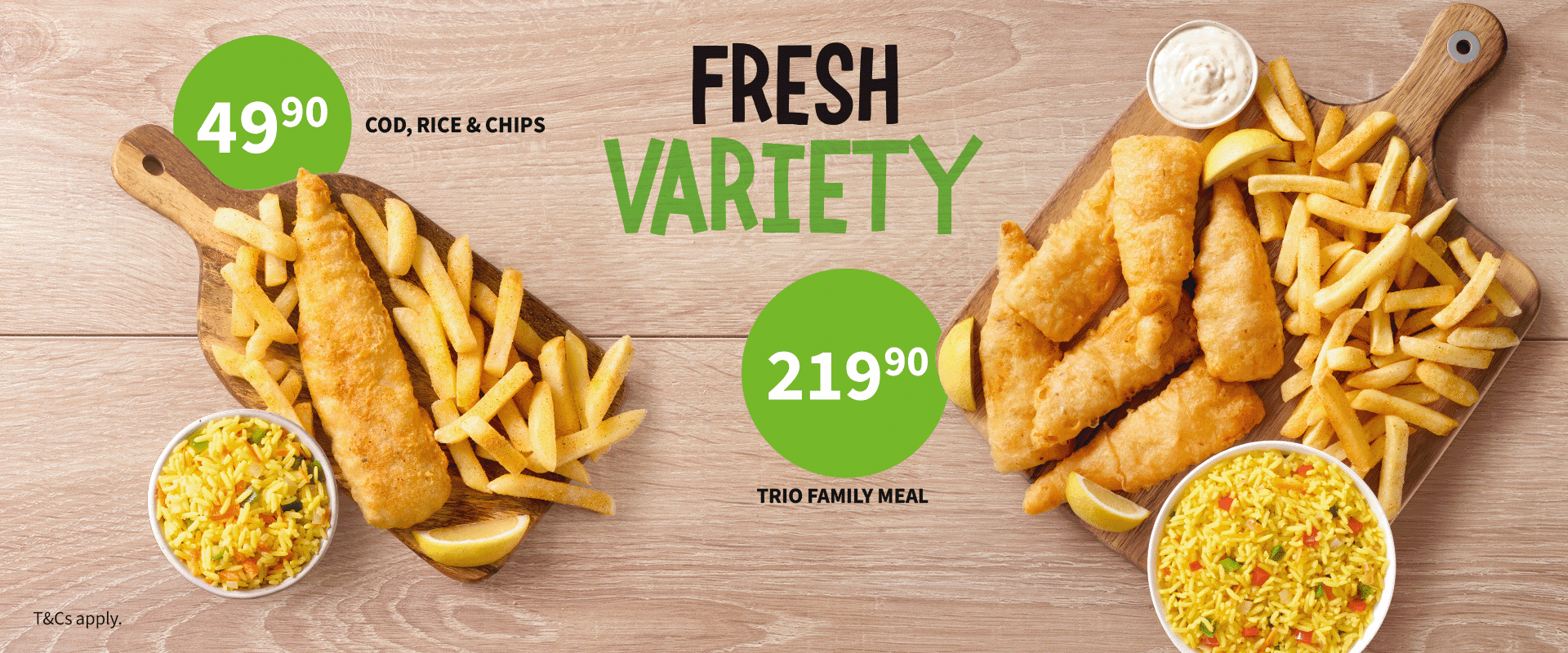 Takeaway lunch meals from Fishaways including seafood lunch box filled with hake fillets, fish pops, hake strips, onion rings, chips and Coke No Sugar against a wooden background.