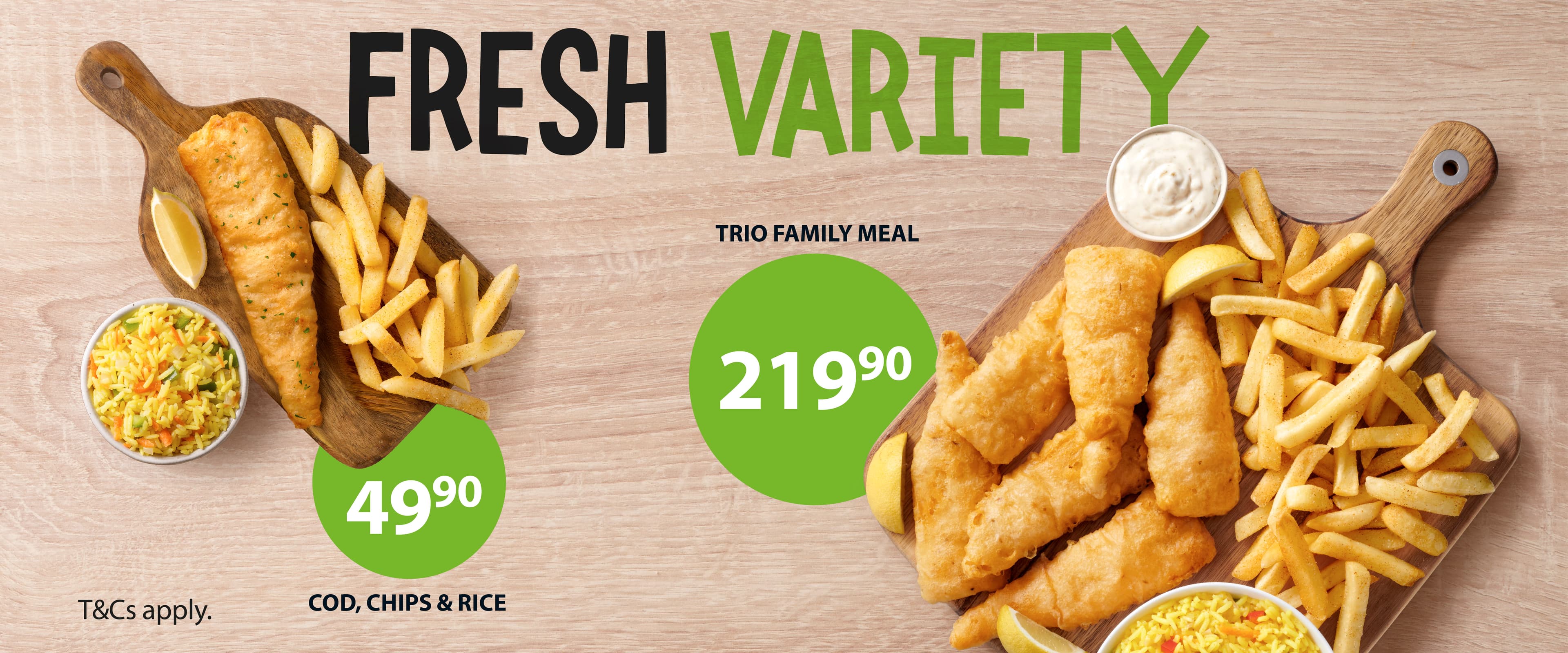 Takeaway lunch meals from Fishaways including seafood lunch box filled with hake fillets, fish pops, hake strips, onion rings, chips and Coke No Sugar against a wooden background.