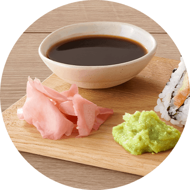 Soy sauce in a bowls with ginger and wasabi on a wooden board